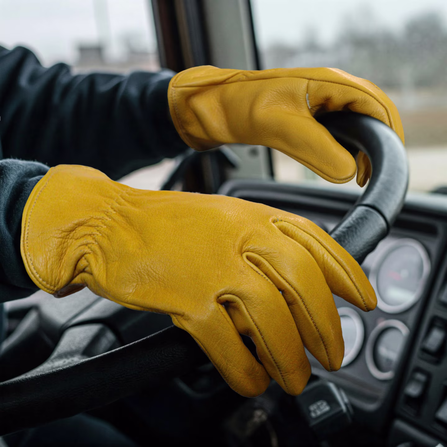 Conductor con guantes de cuero sujetando el volante de un camión